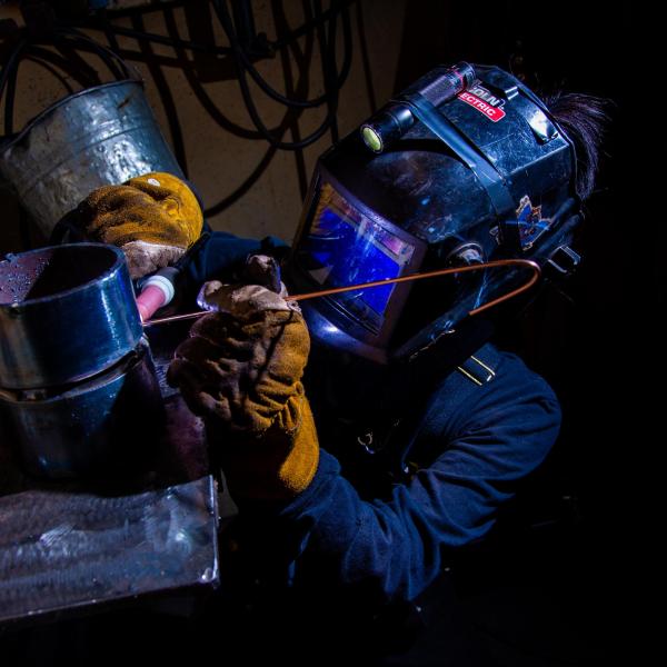 A female VIU student is preparing to weld a pipe. 