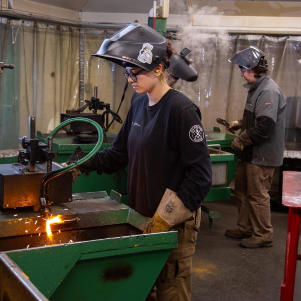 A welding student pauses next to equipment as she considers her next move. 