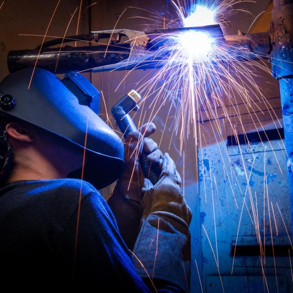 Orange welding sparks rain down on a VIU welding student as they do their work.  