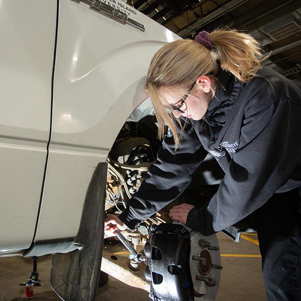 A woman working on a car tire. 