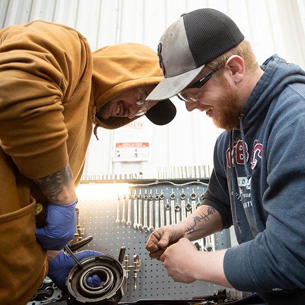 Two young men working together at a workbench. 