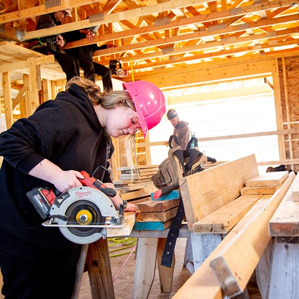 A woman using a skill saw on a construction site. 
