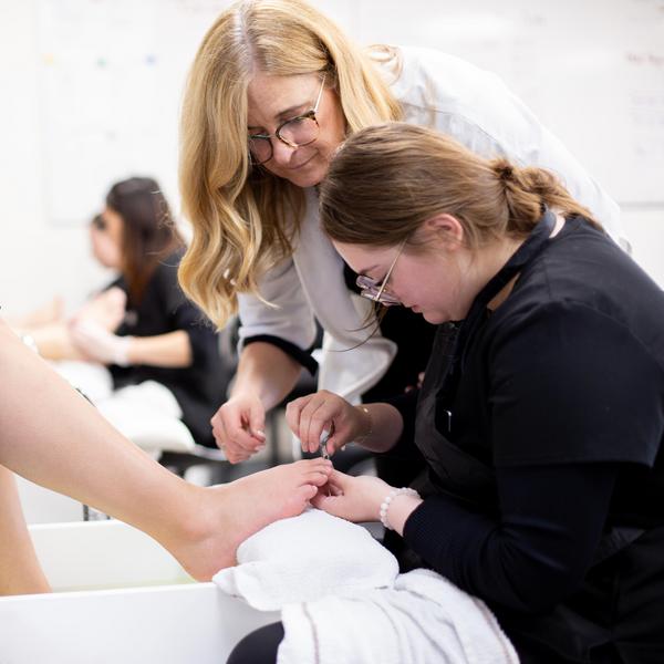 a student gives a client a pedicure with the oversight of an instructor 