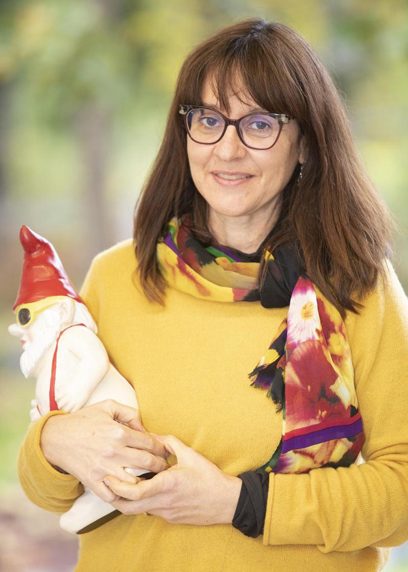 A woman holding two garden gnomes.