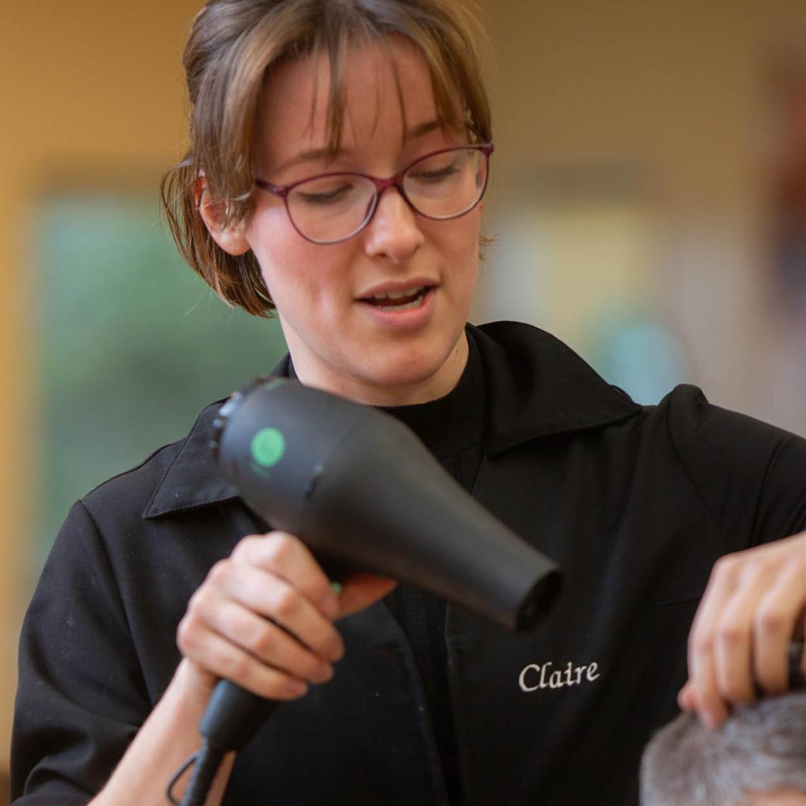 Young woman blow-drying someone's hair. 