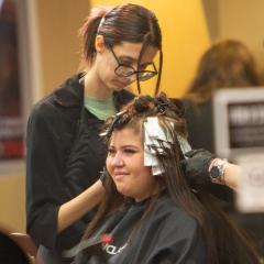 Young woman putting highlighting foils in a woman's hair.
