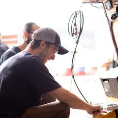 a man in a ball cap looking at controls in an RV. 